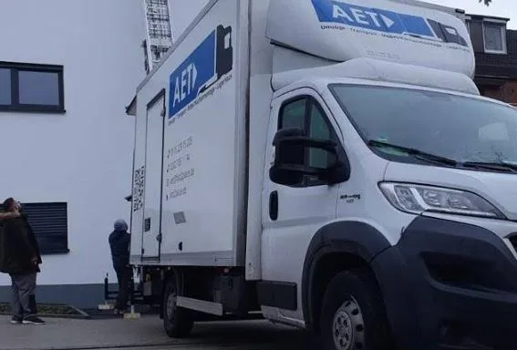 Umzugsfahrzeug von AET Umzüge parkt vor einem Gebäude