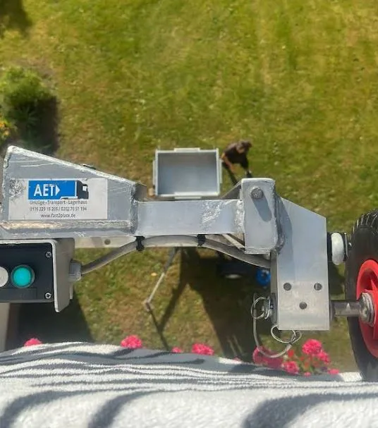 Möbellift hebt eine Transportkiste über einen Garten